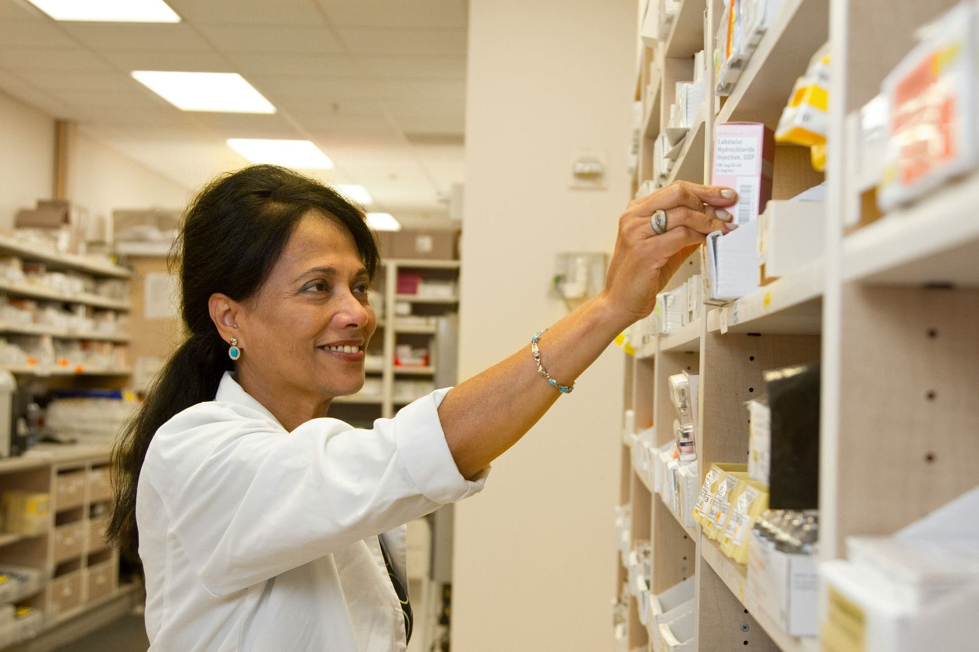 image of pharmacist taking medicine off shelf